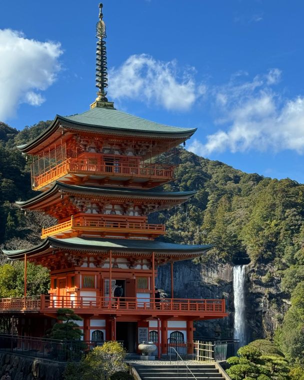 Pagoda junto a una cascada, entre laderas boscosas
